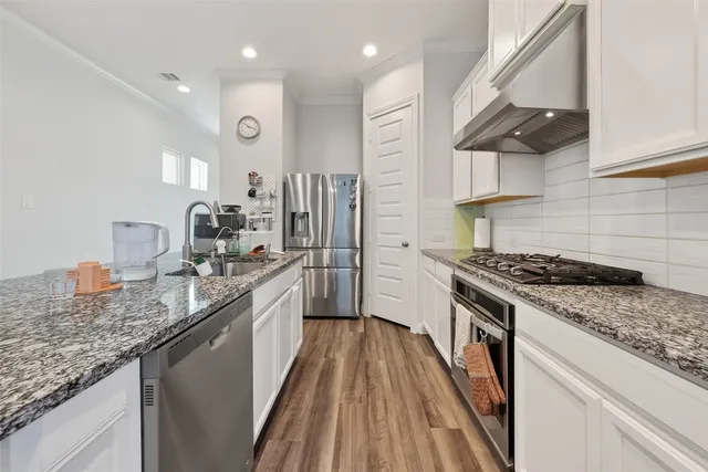 a kitchen with stainless steel appliances granite countertop a stove a sink and a refrigerator