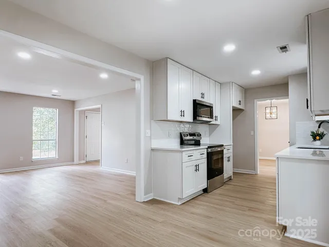 a kitchen with stainless steel appliances granite countertop a stove top oven a sink dishwasher and a refrigerator with wooden floor