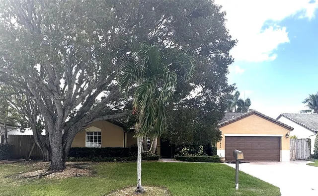 a front view of a house with a garden and trees