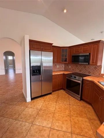 a kitchen with stainless steel appliances granite countertop a refrigerator and a stove top oven