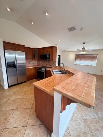 a kitchen with stainless steel appliances kitchen island granite countertop a refrigerator a stove a sink and a microwave