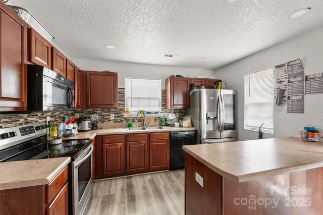 a kitchen with kitchen island granite countertop a sink stove and refrigerator