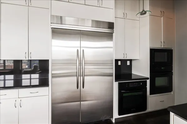 a kitchen with refrigerator stove and couches with wooden floor