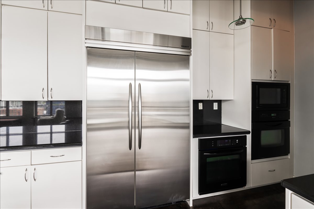 311 West 5th Street, Unit 1005 Austin, TX 78701 - Photo 12 of 30 A designer kitchen showcasing a tasteful backsplash, premium appliances including an industrial-size refrigerator, blending refined design with elevated functionality.