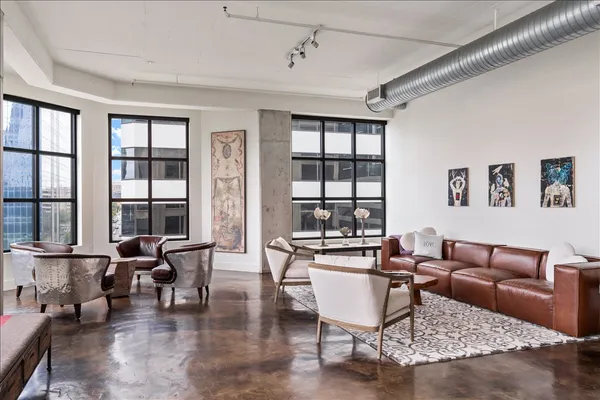 a living room with furniture large window and wooden floor