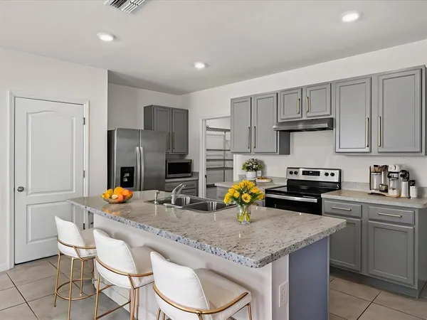 a kitchen with a sink a stove and chairs