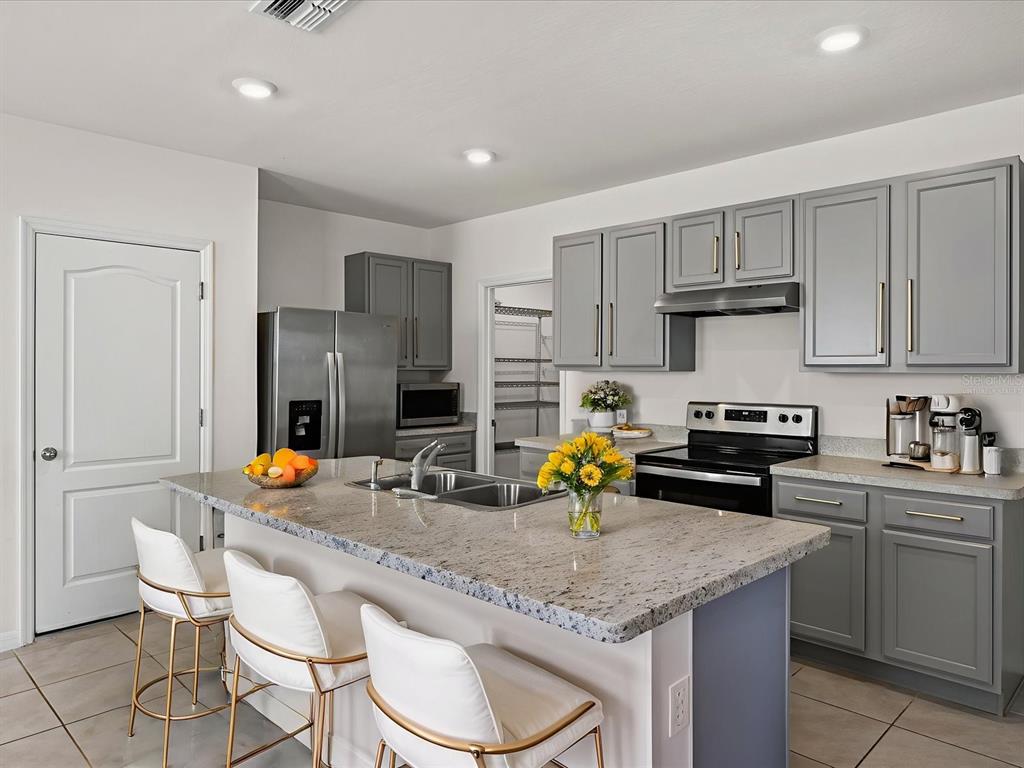 4223 San Rocco Way Winter Haven, FL 33884 - Photo 8 of 47 a kitchen with a sink a stove and chairs