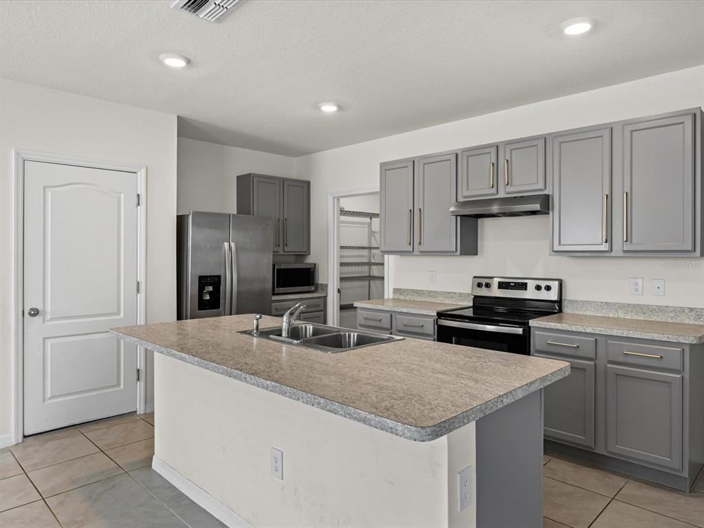 4223 San Rocco Way Winter Haven, FL 33884 - Photo 9 of 47 a kitchen with stainless steel appliances granite countertop a sink stove and refrigerator