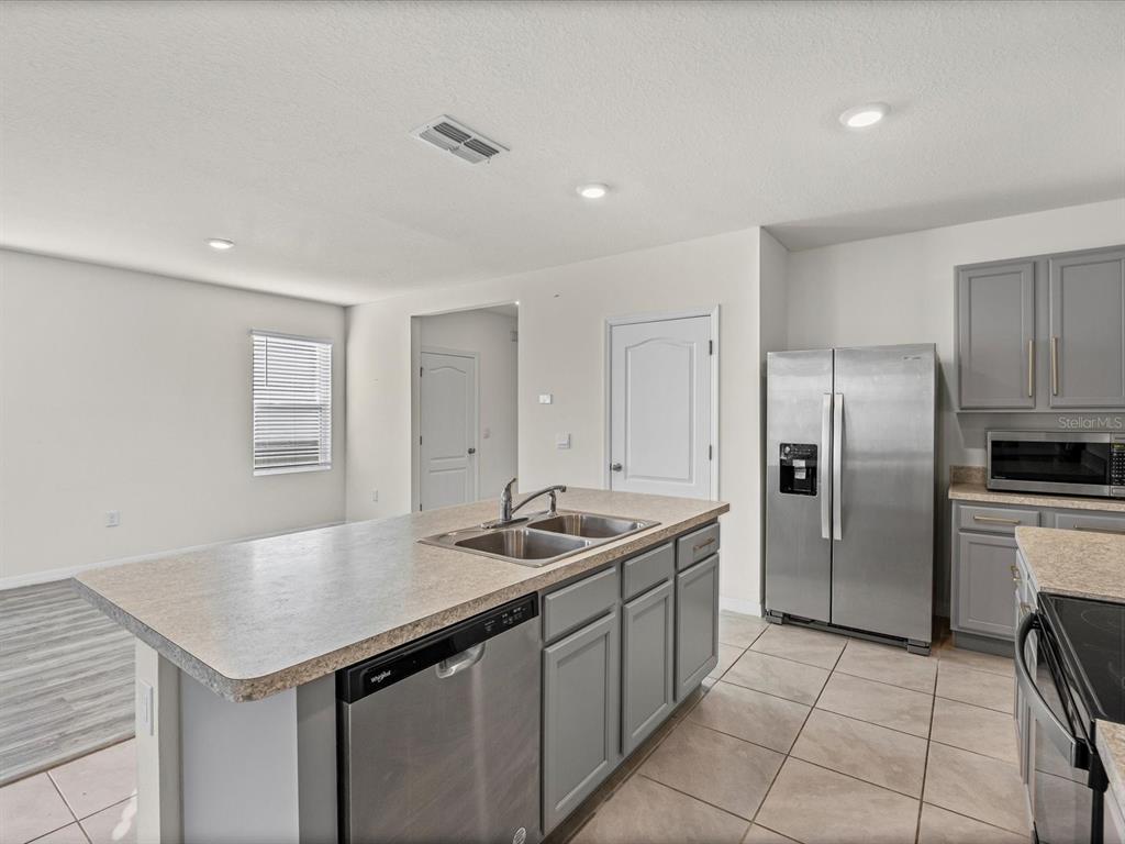 4223 San Rocco Way Winter Haven, FL 33884 - Photo 10 of 47 a kitchen with stainless steel appliances granite countertop a sink refrigerator and cabinets
