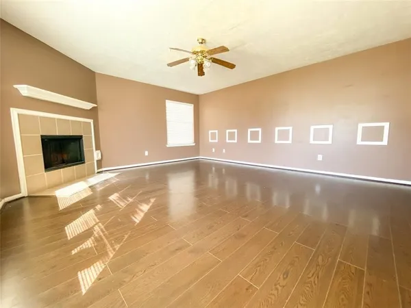 a view of an empty room with a window and wooden floor