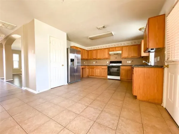 a large kitchen with granite countertop a stove a sink and a refrigerator