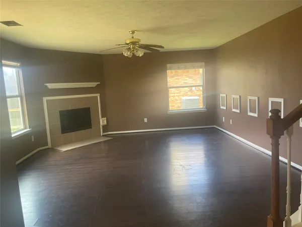a view of an empty room with window and wooden floor
