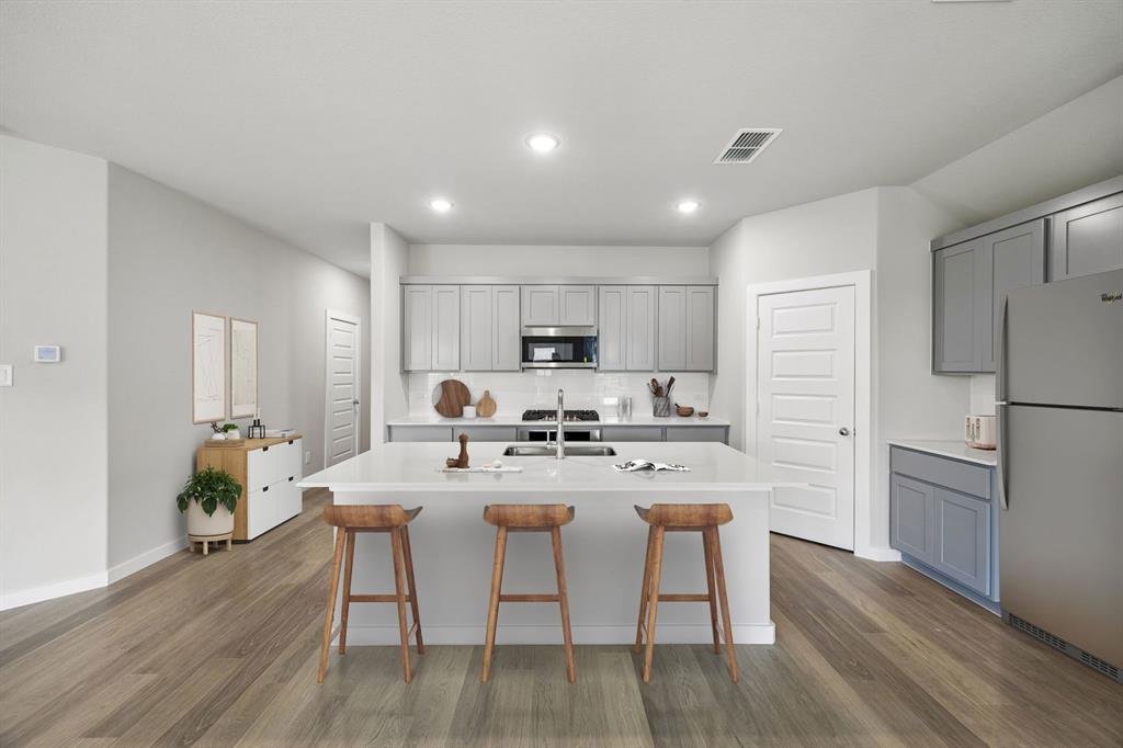 1456 Companero Street Haslet, TX 76052 - Photo 5 of 33 a kitchen with stainless steel appliances granite countertop a dining table chairs refrigerator and microwave