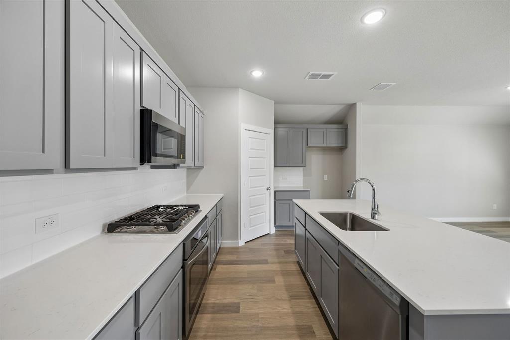 1456 Companero Street Haslet, TX 76052 - Photo 8 of 33 a kitchen that has a sink and a stove