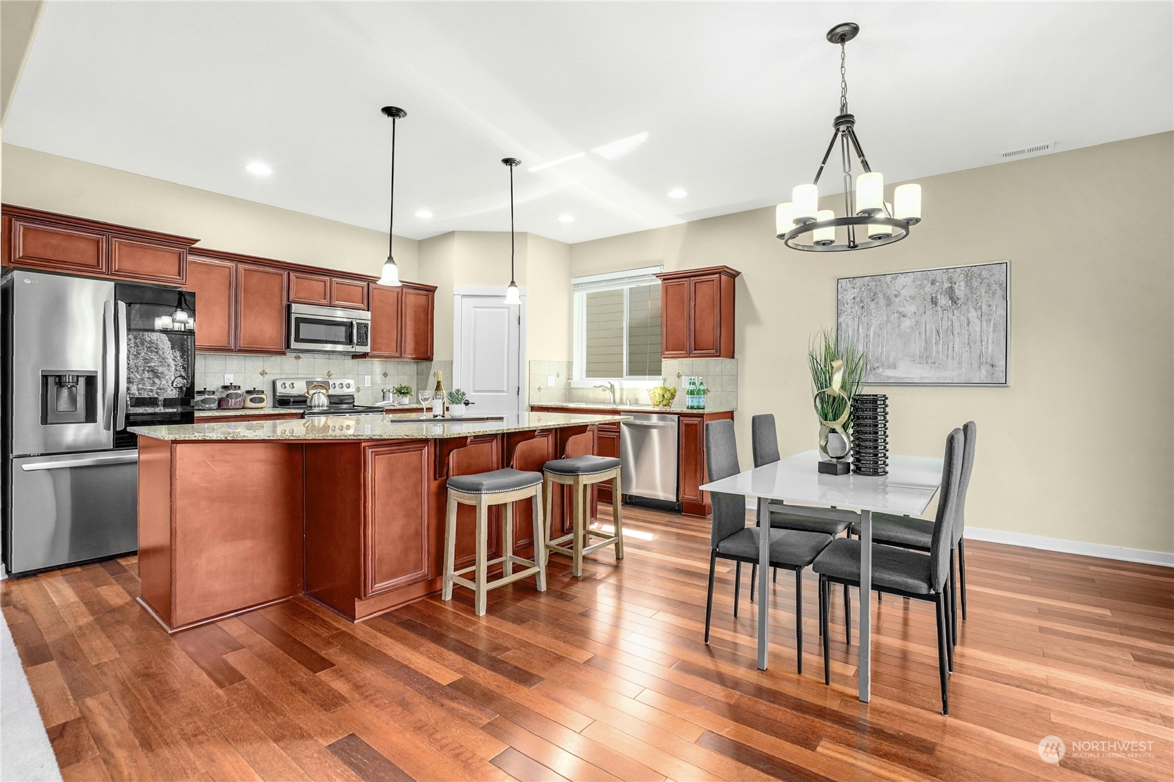 5214 Northeast 7th Street Renton, WA 98059 - Photo 6 of 20 a open kitchen with stainless steel appliances granite countertop a stove a refrigerator a kitchen island a dining table and chairs with wooden floor