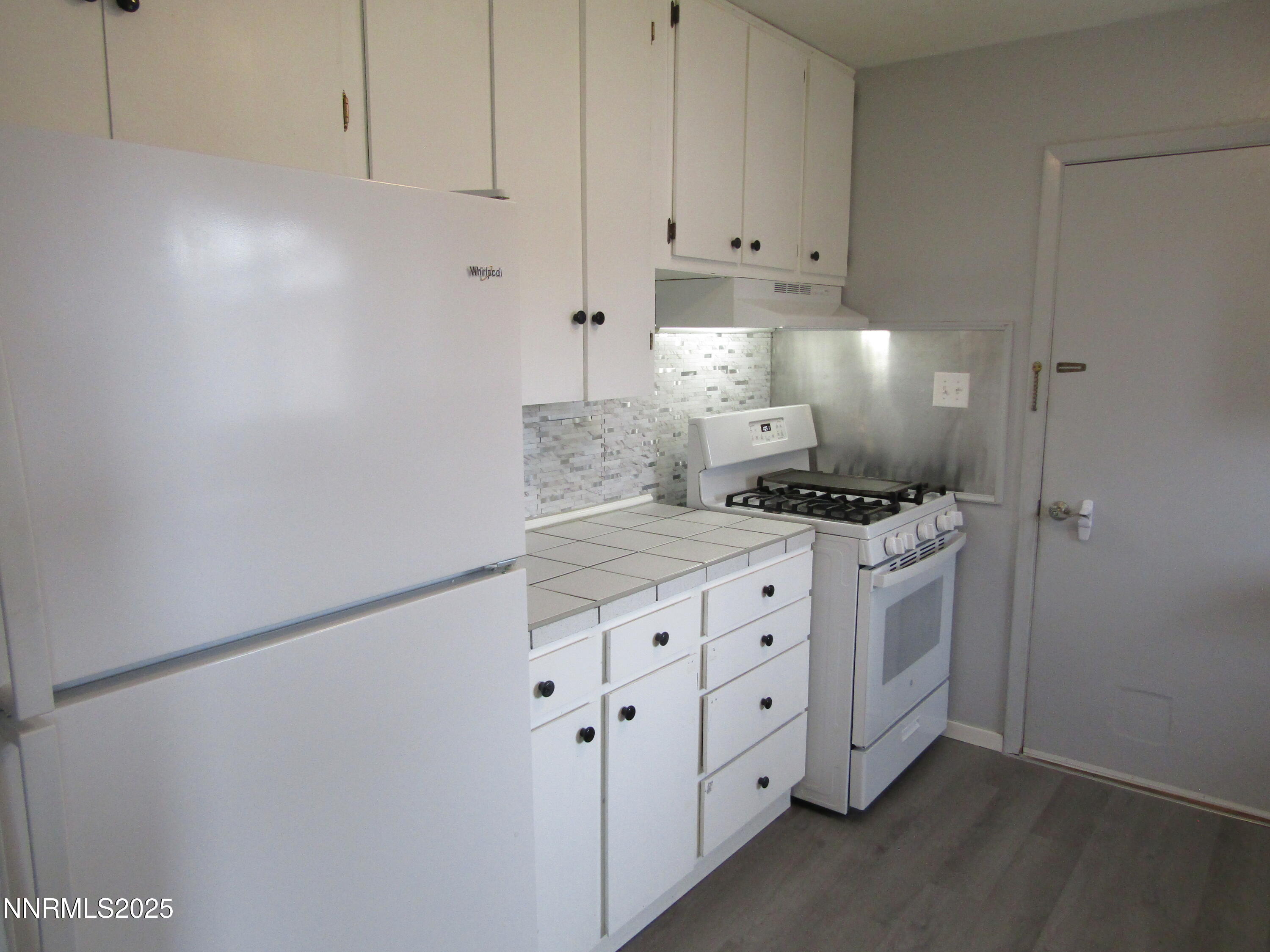 111 South Whitacre Street Yerington, NV 89447 - Photo 11 of 30 a kitchen with granite countertop white cabinets and white appliances