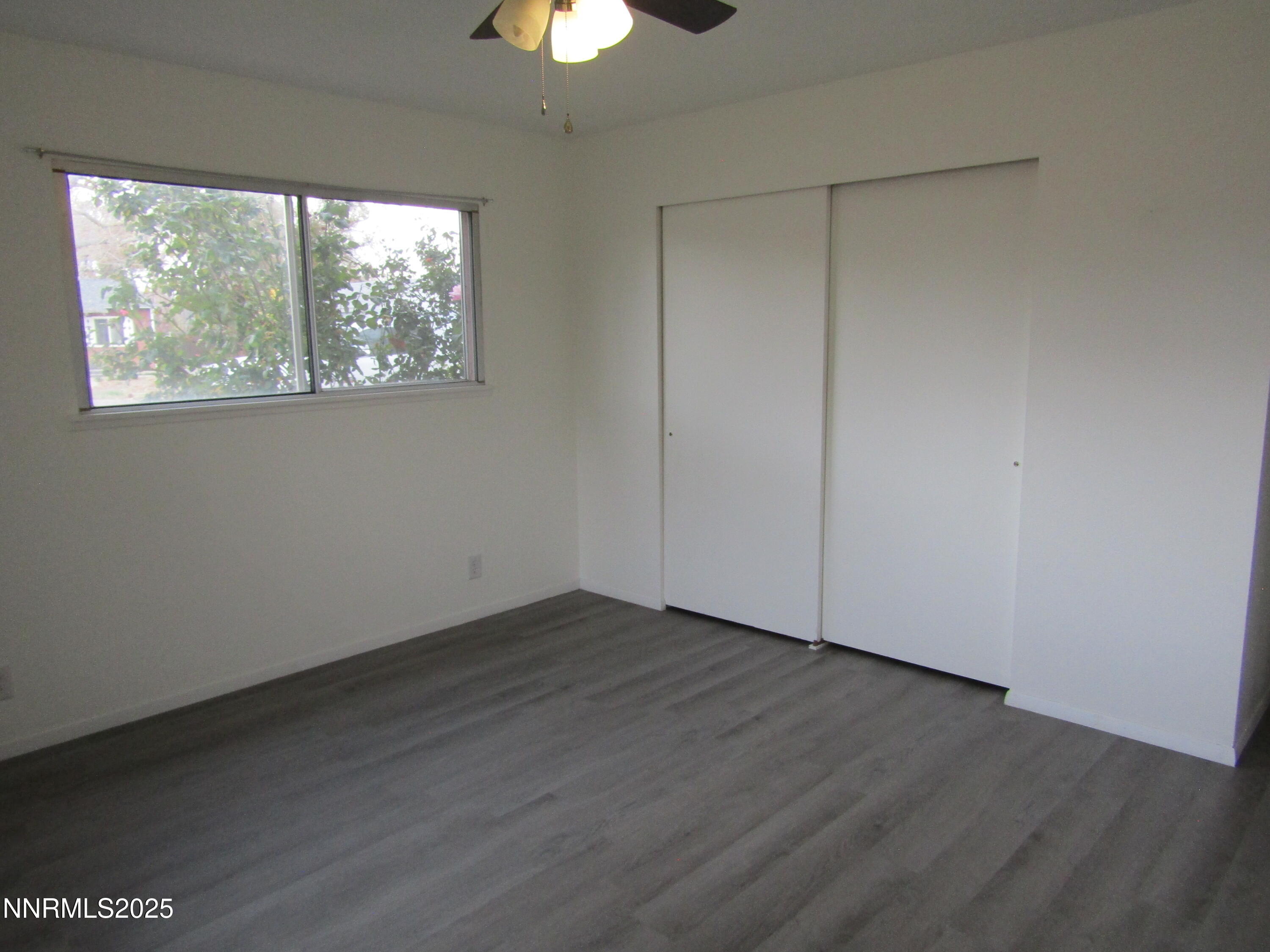 111 South Whitacre Street Yerington, NV 89447 - Photo 19 of 30 an empty room with wooden floor chandelier fan and windows