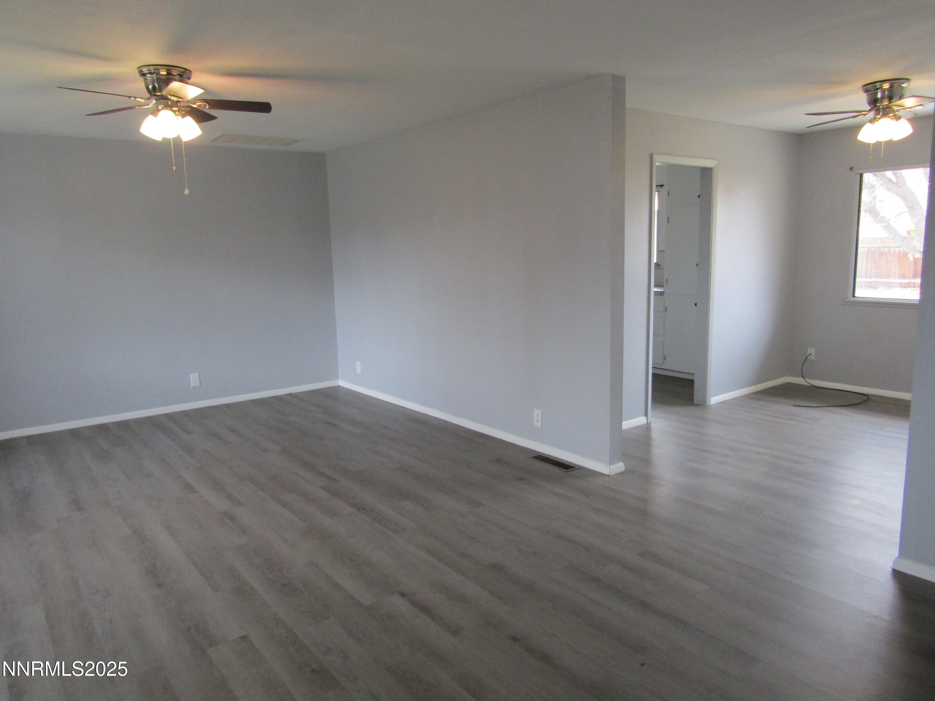 111 South Whitacre Street Yerington, NV 89447 - Photo 3 of 30 an empty room with wooden floor chandelier fan and windows