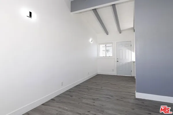 a view of an empty room with wooden floor and windows