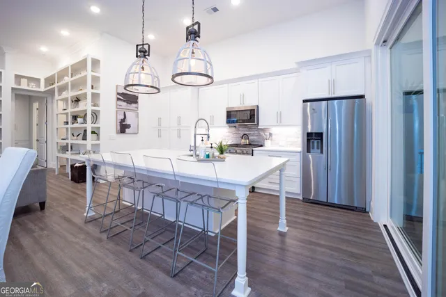 a kitchen with stainless steel appliances a kitchen island hardwood floor and a sink