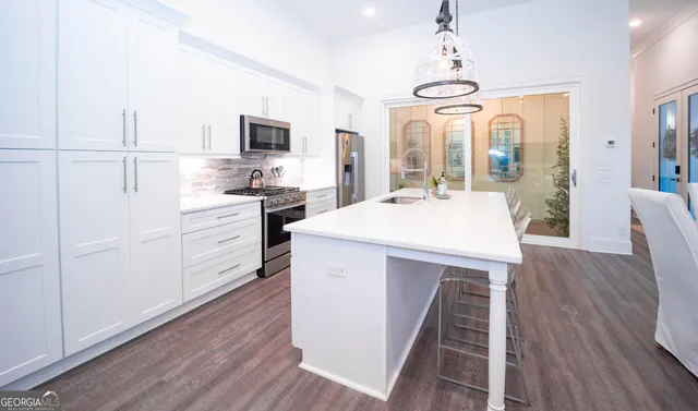 a large kitchen with kitchen island a large counter space a sink appliances and cabinets