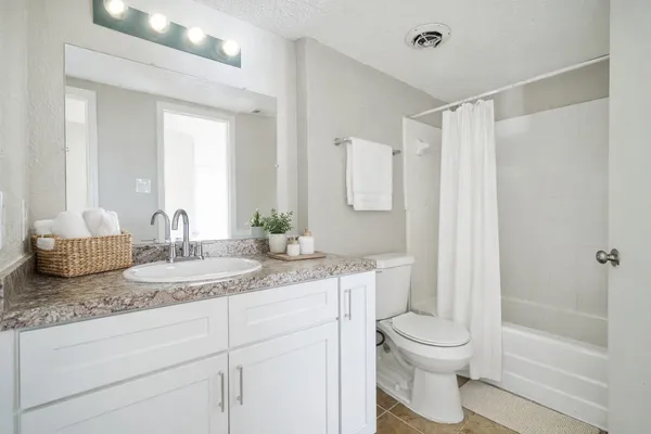 a bathroom with a granite countertop sink mirror vanity and toilet