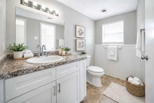 a bathroom with a granite countertop sink mirror and toilet