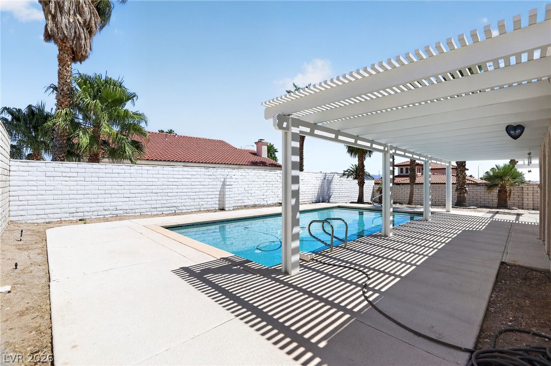 3698 Laughlin Boulevard Laughlin, NV 89029 - Photo 49 of 49 An inviting backyard oasis offers a sparkling in-ground pool, complemented by a shaded patio with a modern pergola.