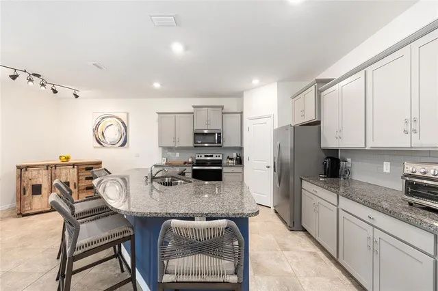 a kitchen with stainless steel appliances granite countertop a kitchen island a stove a table and chairs