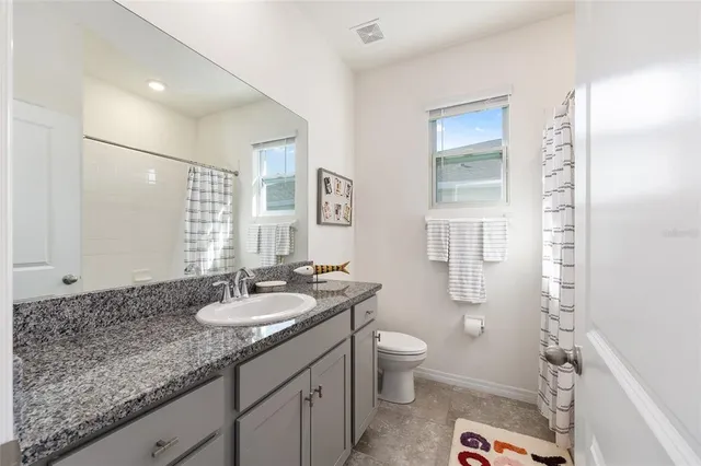 a bathroom with a granite countertop sink a toilet a mirror and shower