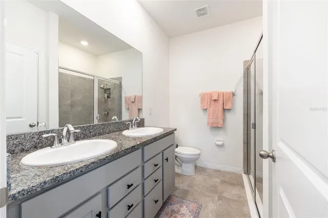 a bathroom with a granite countertop sink toilet and shower