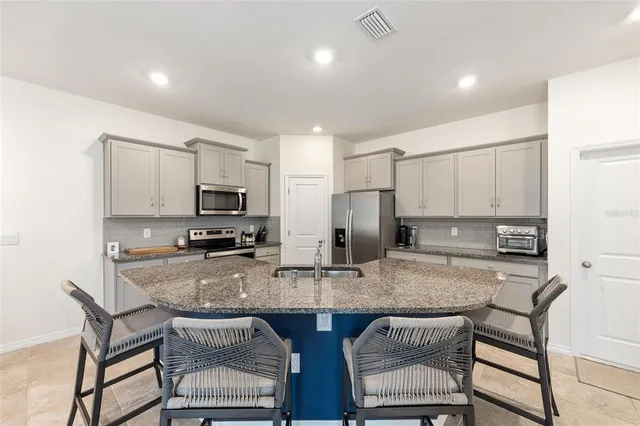 a kitchen with stainless steel appliances granite countertop a table chairs sink refrigerator and microwave