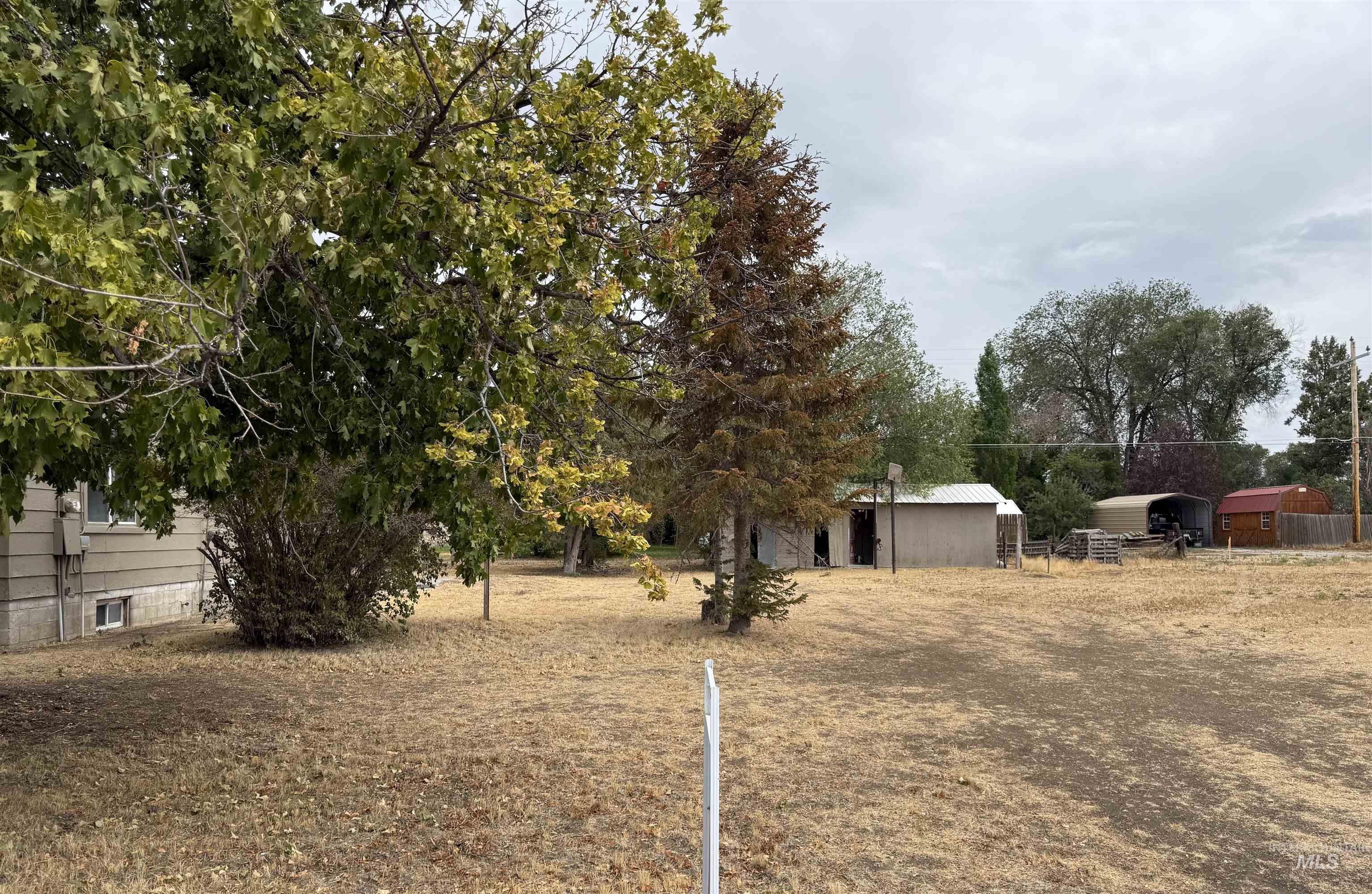 View of yard with an outdoor structure, a pole building, a detached carport, and view of wooded area