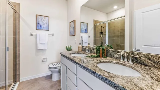 a bathroom with a granite countertop sink a toilet a mirror and shower