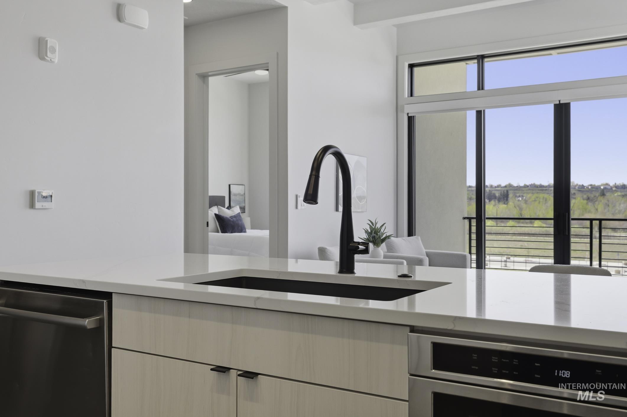 4250 East Haystack Street, Unit 308 Boise, ID 83716 - Photo 11 of 27 Kitchen featuring light stone countertops, stainless steel appliances, modern cabinets, and beam ceiling