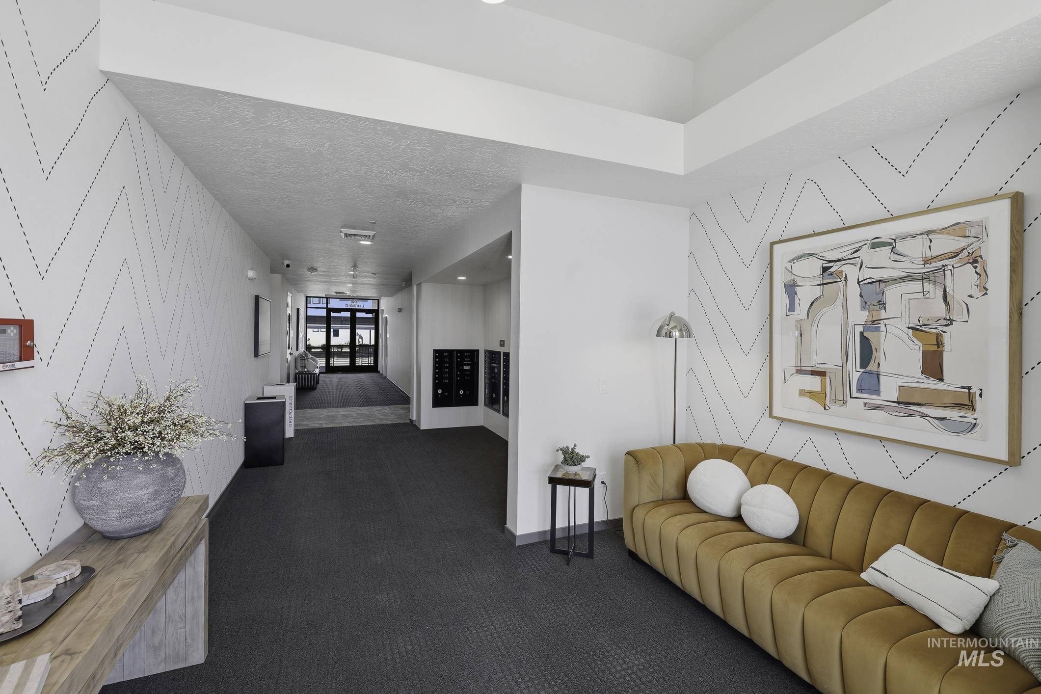 4250 East Haystack Street, Unit 308 Boise, ID 83716 - Photo 25 of 27 Hallway featuring an accent wall, wallpapered walls, and dark colored carpet