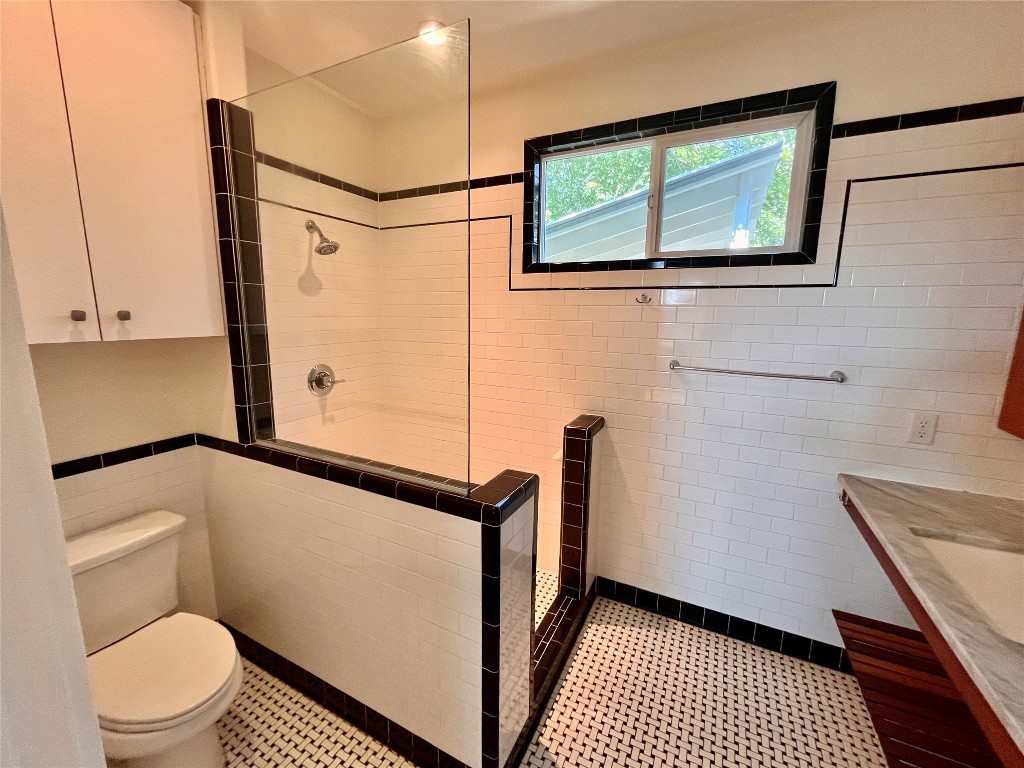 2209 East 18th Street, Unit A Austin, TX 78702 - Photo 12 of 35 Full bath with tile walls, walk in shower, vanity, and wainscoting