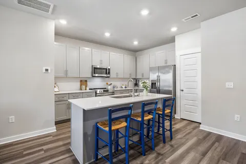 a kitchen with stainless steel appliances granite countertop a table chairs sink refrigerator and microwave
