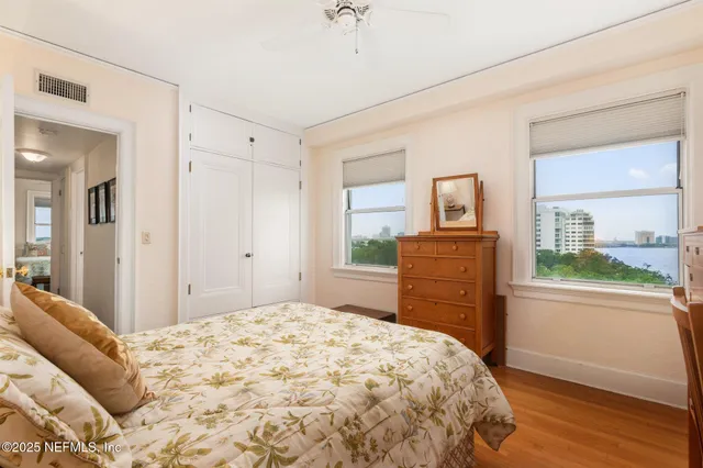 a bedroom with a bed dresser and a large window
