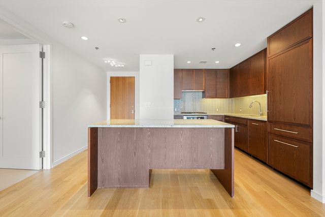 a kitchen with kitchen island a counter top space wooden cabinetry and stainless steel appliances