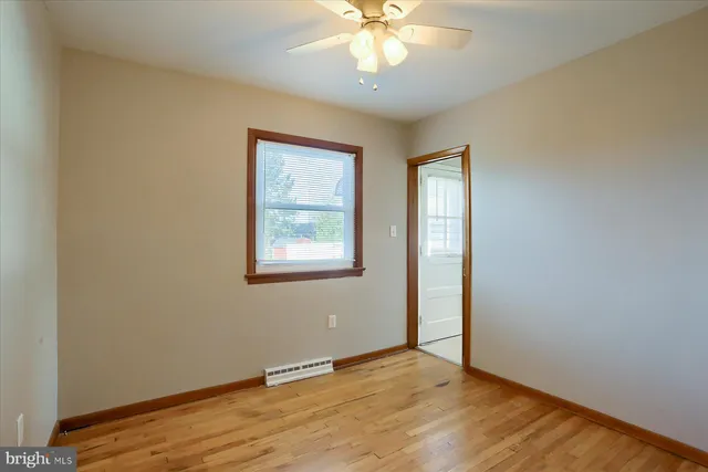 an empty room with wooden floor chandelier fan and windows