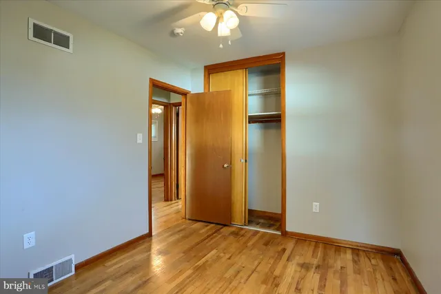 an empty room with wooden floor and a ceiling fan