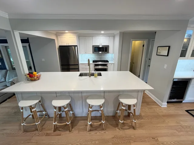 a kitchen with stainless steel appliances a dining table chairs and refrigerator