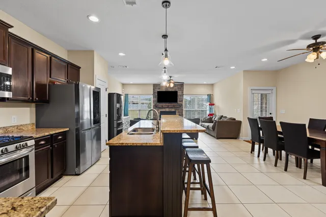 a large kitchen with stainless steel appliances kitchen island granite countertop a table chairs and a refrigerator