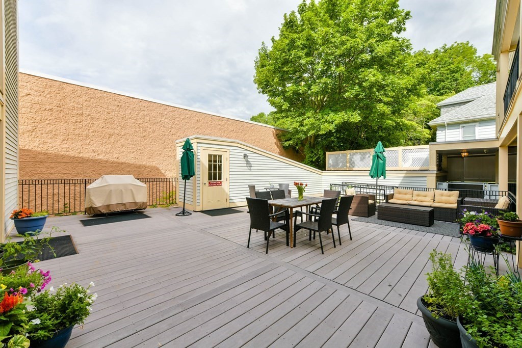 2 Lee Hill Road, Unit 6 Boston, MA 02131 - Photo 21 of 42 a view of a patio with table and chairs potted plants with wooden floor and fence