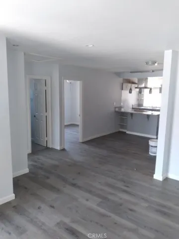 a big room with wooden floor and kitchen view