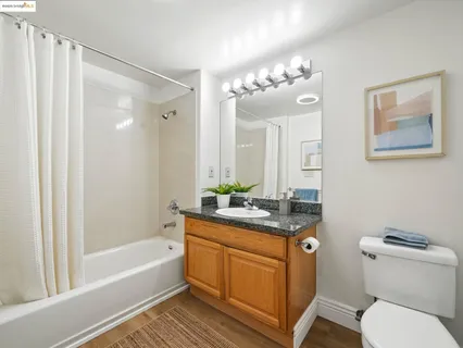 a bathroom with a granite countertop sink a toilet a mirror a vanity a bathtub and shower