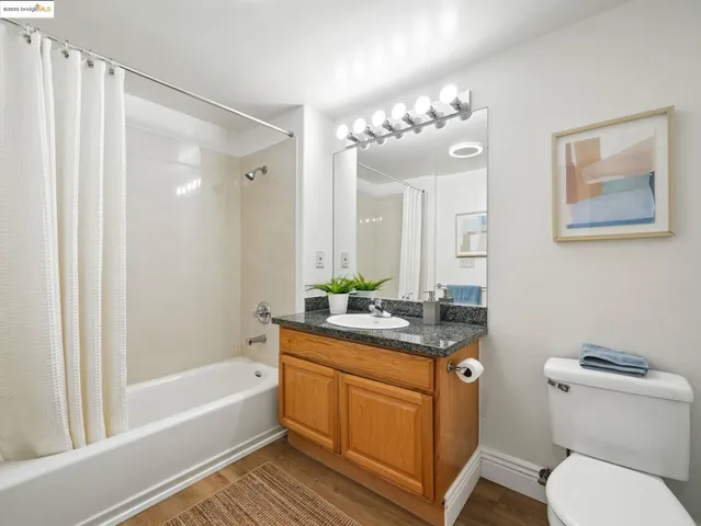 a bathroom with a granite countertop sink a toilet a mirror a vanity a bathtub and shower