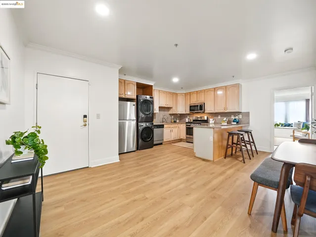 a kitchen with stainless steel appliances kitchen island granite countertop a refrigerator and a dining table