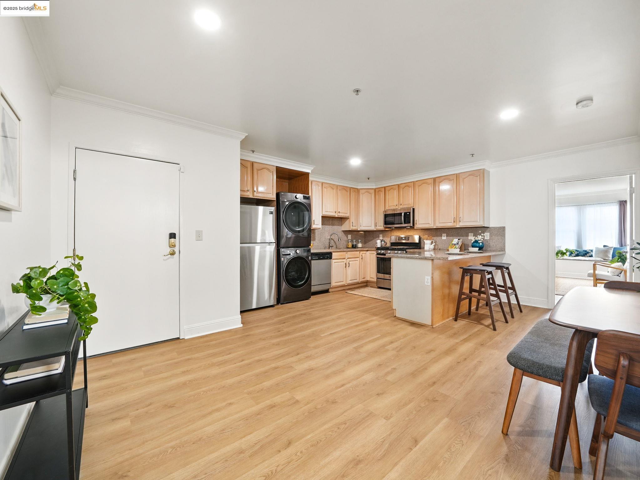 1515 14th Avenue, Unit 201 Oakland, CA 94606 - Photo 5 of 23 a kitchen with stainless steel appliances kitchen island granite countertop a refrigerator and a dining table
